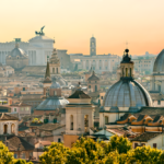 Vista panoramica dell’architettura storica di Roma, inclusi chiese a cupola e monumenti iconici, immersi nella calda luce dell’ora dorata.